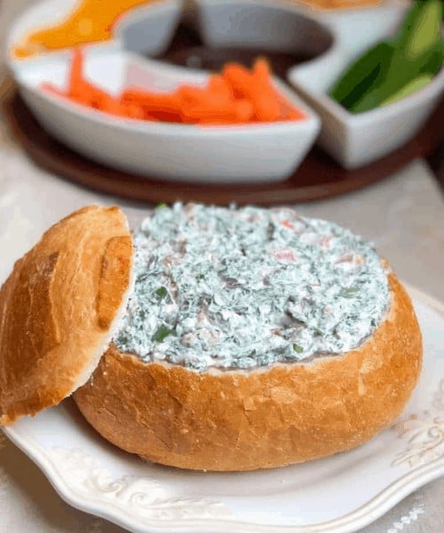 spinach dip inside of a hallowed out round baguette.