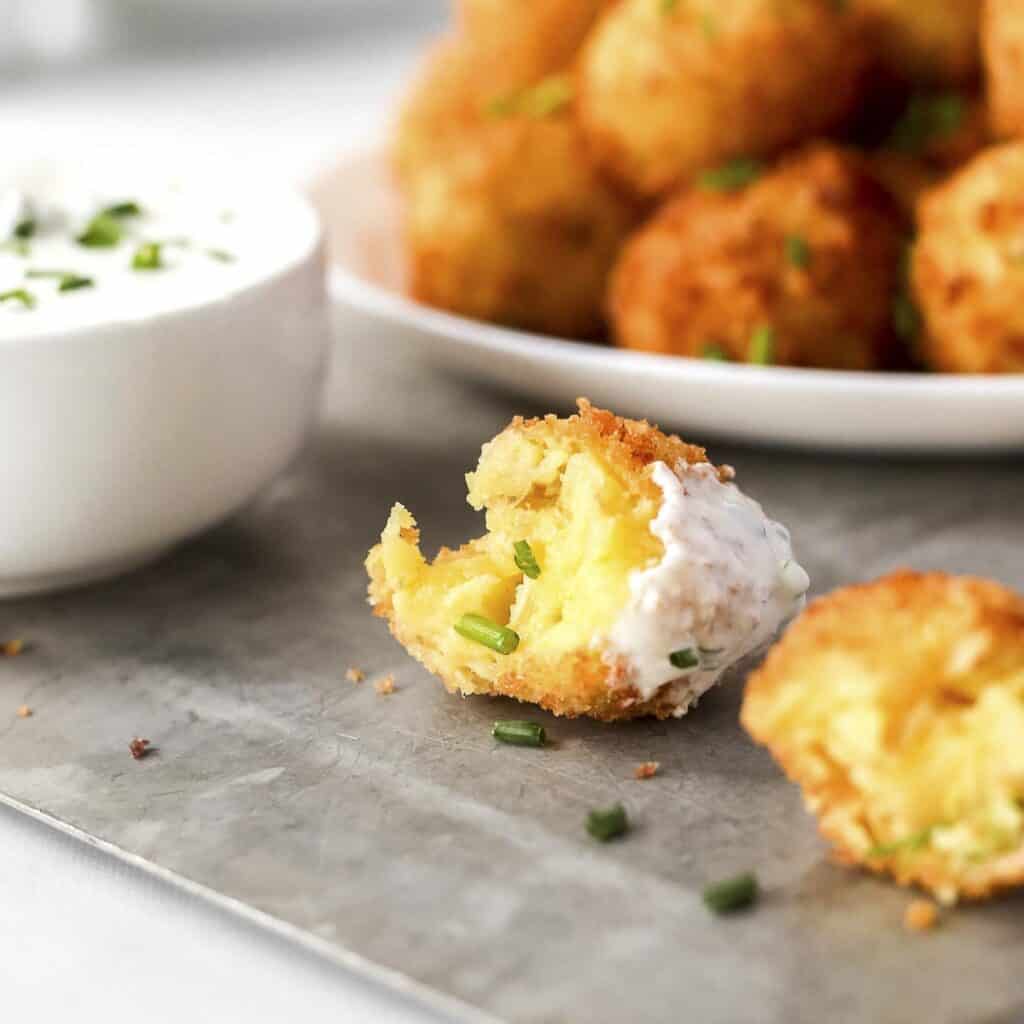 Homemade cheesy potato croquettes with sauce on table.