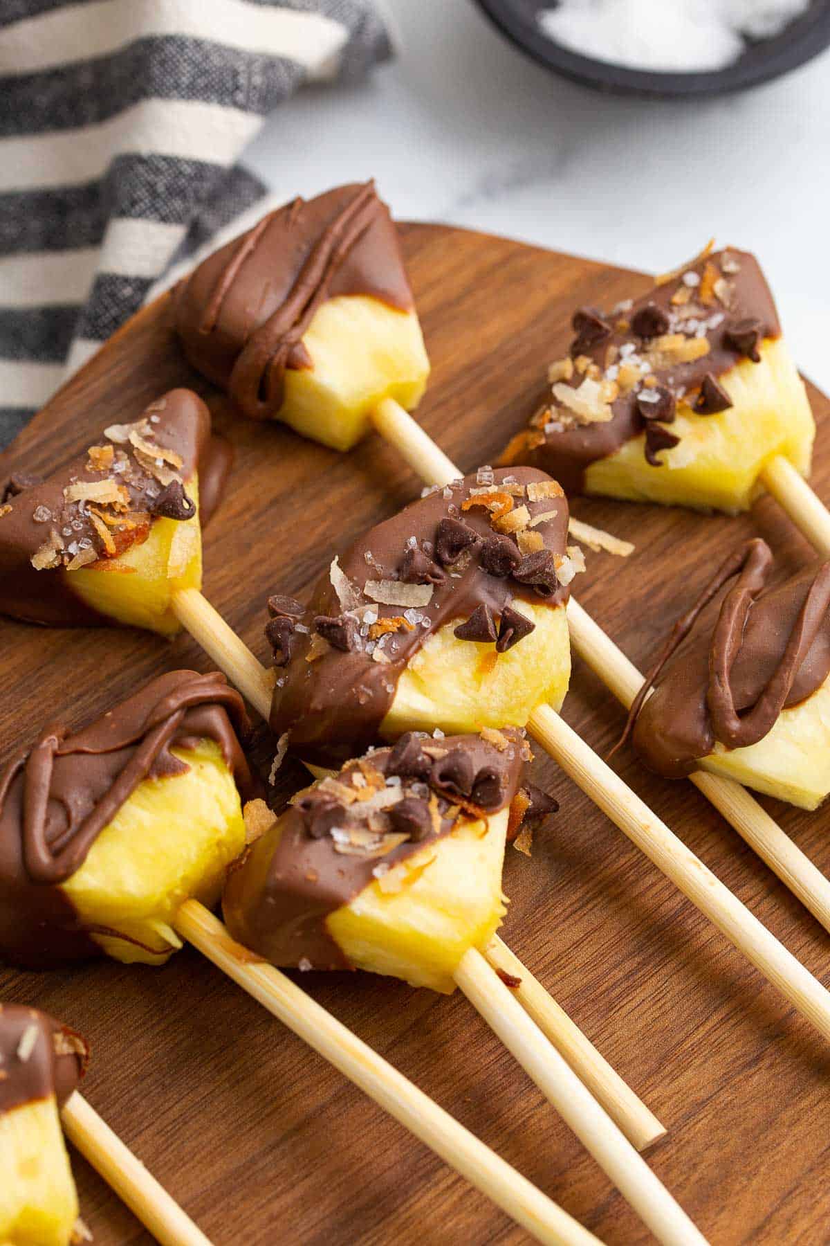 Chocolate dipped pineapple on skewers with coconut.