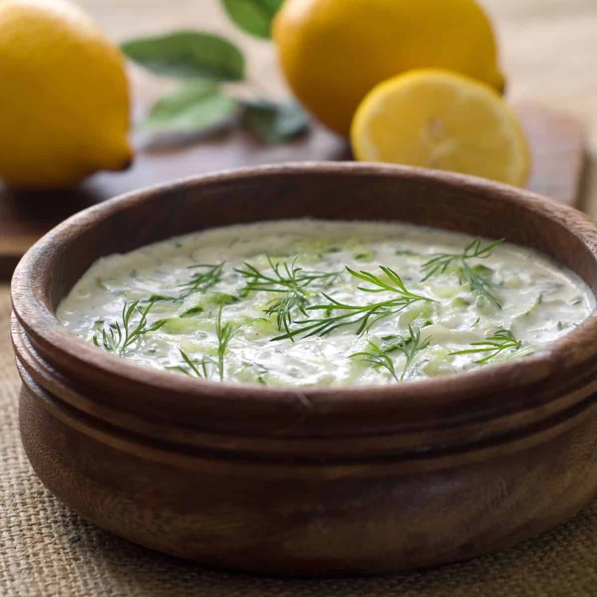 Cold dip in a bowl with lemons on table.