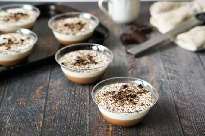 Tiramisu dessert cups on table with chocolate shavings.